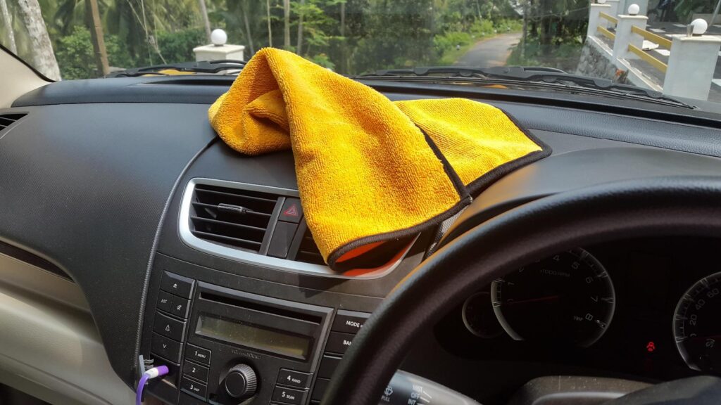 A yellow color microfiber car cloth is placed on car dashboard.