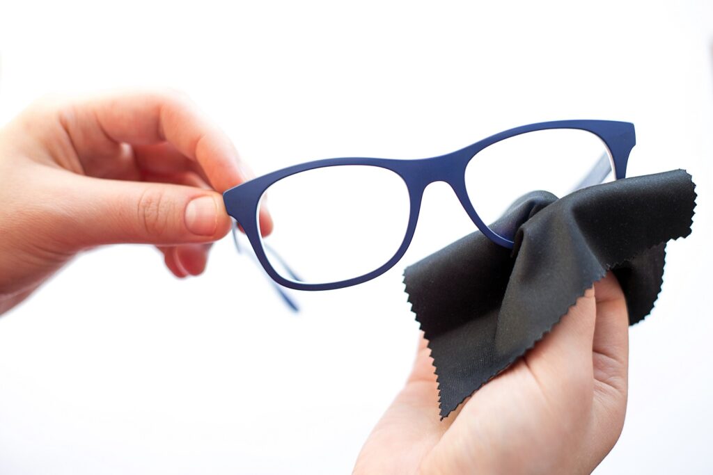 female hands cleaning the spectacles with a black color suede microfiber cloth